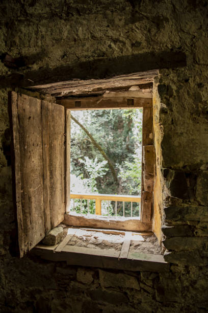 istock View of trees from inside historic stone building, through window opening with wood shutter 1411802333