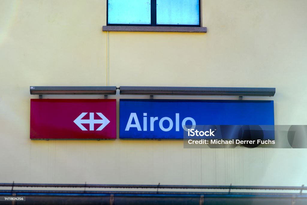 Red and blue sign at facade of railway station building at mountain village of Airolo. Photo taken June 25th, 2022, Airolo, Switzerland. Logo Stock Photo