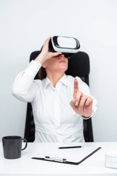 istock Businesswoman Wearing Virtual Reality Goggles And Learning Professional Skill Through Futuristic Simulation. Woman Gesturing While Sitting At Desk During Modern Training. 1411811526