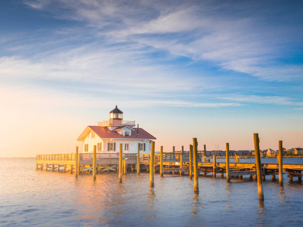 Sunrise Outer Banks Manteo Lighthouse OBX North Carolina Roanoke Island Marshes Lighthouse is located on the lovely waterfront park on the Arbemarle Sound. Two other lighthouses built in the 1800s carried the Roanoke Marshes Light name and were lost or abandoned due to extensive and neglected repairs and a compromised foundation from the challenges of its environment. The current Roanoke Marshes Lighthouse is a replica of the third lighthouse to carry that same name constructed in 1877 on the southern end of the Croatan Sound in the village of Wanchese on Roanoke Island. Local sailors and fisherman could find safe passage to the island with help from this little light. bodie island stock pictures, royalty-free photos & images