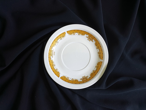 Top view of a plate with a spoon and fork at the right side shot against a wooden table background