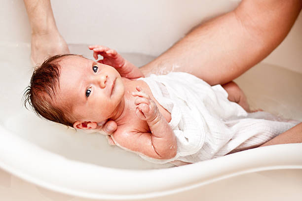 pequeño bebé primer baño - bebe bañandose fotografías e imágenes de stock