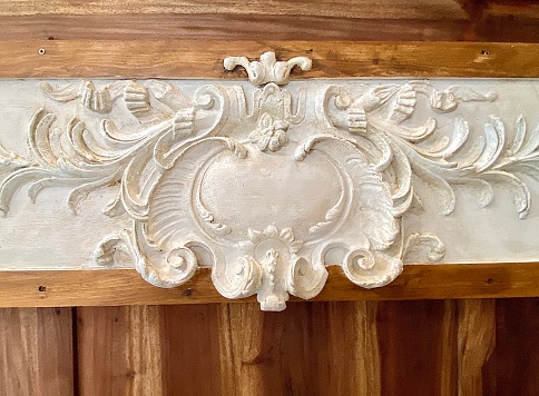 Horizontal close up of small section of ornate French provincial porcelain pattern design inlay on wood furniture table piece