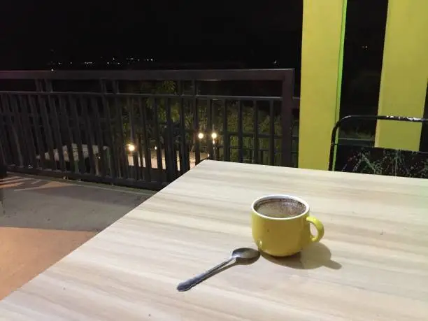 a cup of black coffee with a yellow glass
