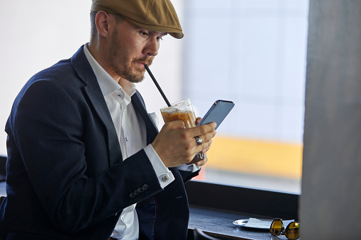 a young businessman trading while drinking his latte at a cafe