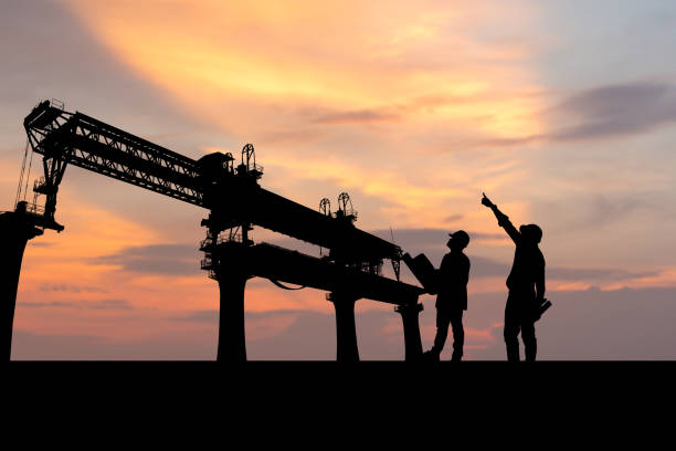 istock Silhouette of Engineer and foreman worker checking project at infrastructure construction site, construction site at sunset in evening 1411818584