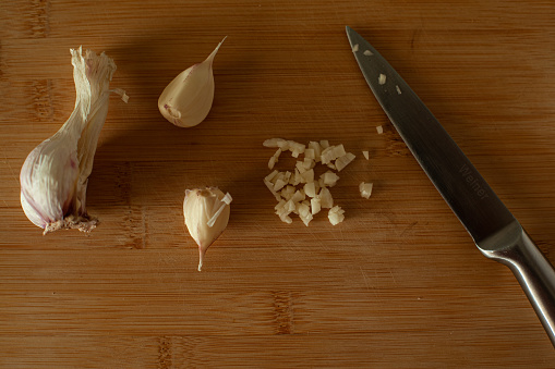 Step 5. Peel and chop garlic. Garlic on cutting board with knife. Cooking roasted beans. DIY. Vegetables on wooden background.