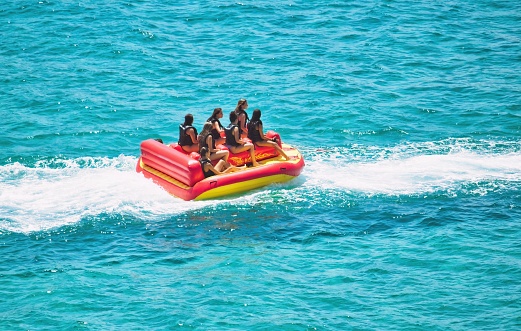 Golden Bay, Mellieha, Malta - July 24 2022: A group of young women on an inflatable raft being towed in the water