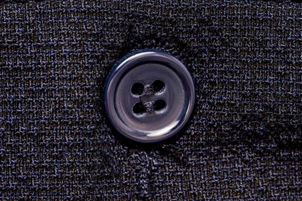 Macro photo of a sewing button on a dark blue fabric pattern isolated background. High quality photo