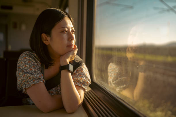 Portrait of young female tourist traveling by train Portrait of young female tourist traveling by train. She is sitting at the seat next to the window and looking outside at the view through the window. train interior stock pictures, royalty-free photos & images