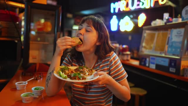 Woman eating taco in a bar
