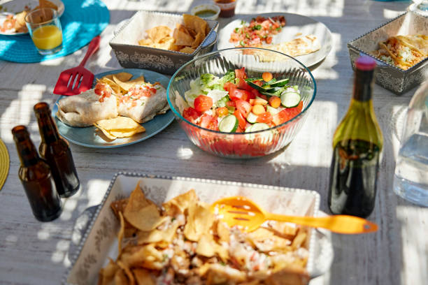 Variety of Latin American dishes on table for outdoor dining Bowl of salad and serving dishes of nachos, tacos, burritos, and beverages sitting on table and ready to be served. florida food stock pictures, royalty-free photos & images