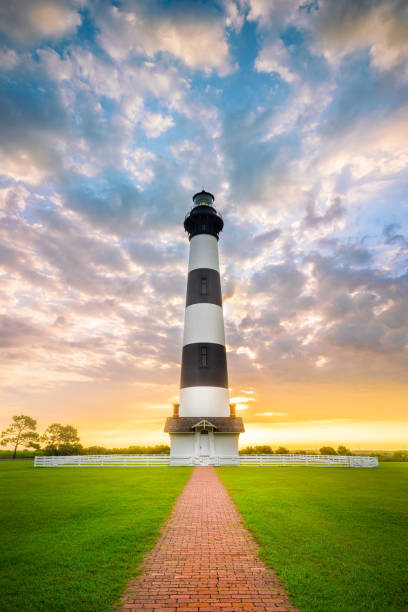 Sunrise Bodie Island Lighthouse OBX Outer Banks NC Part of the beautiful Cape Hatteras National Seashore, the Bodie Island Lighthouse is an Iconic Lighthouse of Nags Head Outer Banks North Carolina. This incredible stretch of coastal barrier islands along the east coast of NC is known for its amazing beaches and abundant wildlife. bodie island stock pictures, royalty-free photos & images