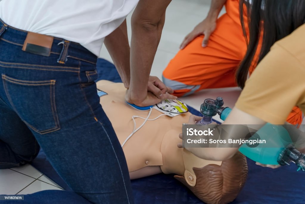 First aid training, Heart pump and uses a ventilator. A male student performs a heart pump, a female student uses a ventilator and a first aid dummy, guided by a speaker. First aid training, EMS, Paramedics. Education Training Class Stock Photo