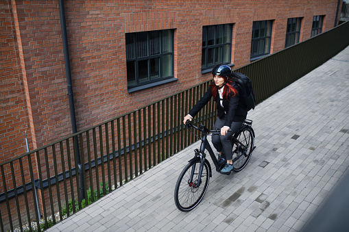 A businesswoman commuter on the way to work with bike, sustainable lifestyle concept. High angle view.
