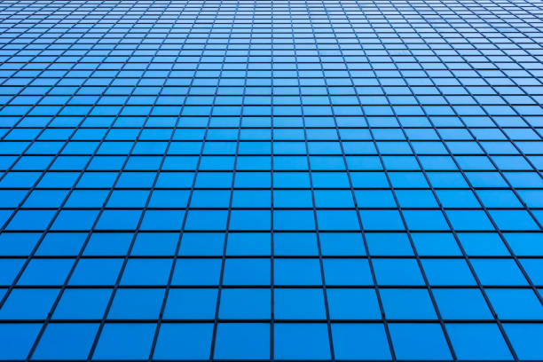 Perspective of the facade of a modern skyscraper with large reflected surfaces made up of regular rectangles.