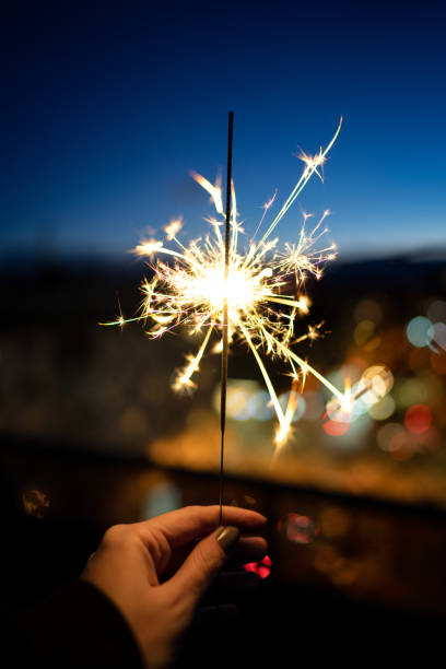 mulher segurando sparkler durante a hora azul - sparkler sparks new years eve human hand - fotografias e filmes do acervo