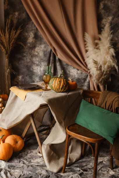 istock Autumn interior: a table covered with dishes, pumpkins, a relaxed composition of Japanese pampas grass. Interior in the photo Studio. Close - up of a decorated autumn table. 1411844982