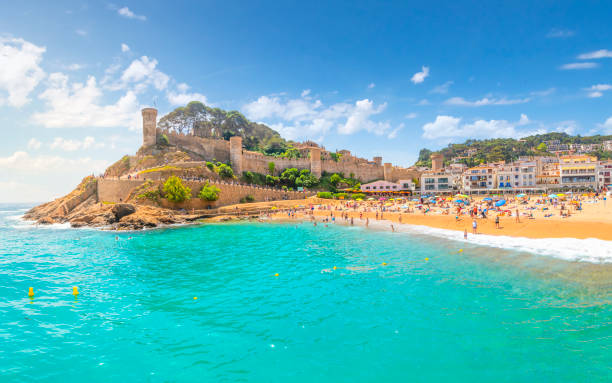 The 12th Century Castle rises above the sandy beach and whitewashed Spanish village of Tossa de Mar, Spain, along the rocky Costa Brava coast at the tourist resort town on a crowded summer day. The 12th Century Castle rises above the sandy beach and whitewashed Spanish village of Tossa de Mar, Spain, along the rocky Costa Brava coast at the tourist resort town on a crowded summer day. tossa de mar stock pictures, royalty-free photos & images