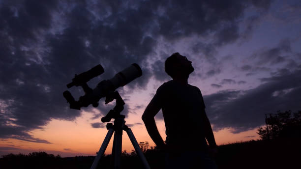 istock Man with astronomical telescope observing night sky, under the Milky way stars. 1411846064