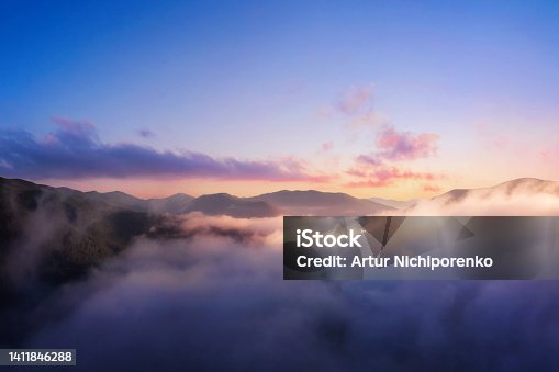 istock Mountains in low clouds. Mountain landscape with dramatic cloudy sky, peaks in fog and bright sunlight at dawn. 1411846288