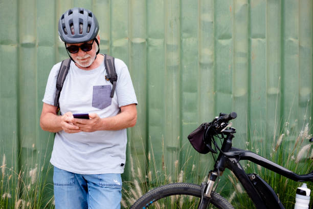 istock Attractive senior man with helmet and backpack using mobile phone while enjoying sport activity with electric bicycle in outdoors - sustainable mobility concept 1411846819