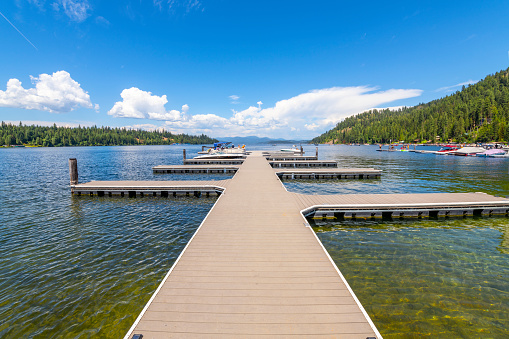 Summer day at Cavanaugh Bay as boats dock in the marina along the sandy beach, vacation cabins and small town on Priest Lake, in Coolin, Idaho.