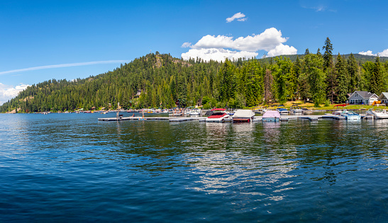 Summer day at Cavanaugh Bay as boats dock in the marina along the sandy beach, vacation cabins and small town on Priest Lake, in Coolin, Idaho.