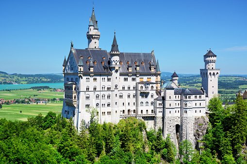 Fussen, Germany - August 7, 2015: Beautiful view of world-famous Neuschwanstein Castle, the nineteenth-century Romanesque Revival palace built for King Ludwig II on a rugged cliff, with scenic mountain landscape near Fussen, southwest Bavaria, Germany.