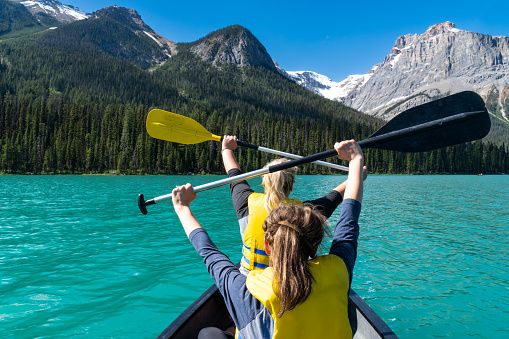 Two adult woman paddle on a canoe on Emerald Lake in Yoho National Park in British Columbia Canada
