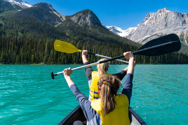 two adult woman paddle on a canoe on emerald lake in yoho national park in british columbia canada - british columbia canada lake emerald lake imagens e fotografias de stock