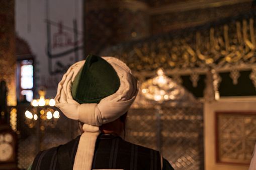 Senior muslim man is praying in the Mevlana Tomb mosque