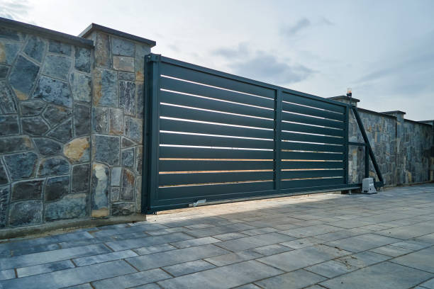 wide automatic sliding gate with remote control installed in high stone fense wall. security and protection concept - ingang stockfoto's en -beelden