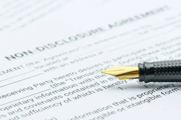 Photo of Business legal document concept : Pen on a mutual confidentiality agreement form. Confidentiality agreement is legal contract between 2 or bilateral parties that outlines confidential issues together