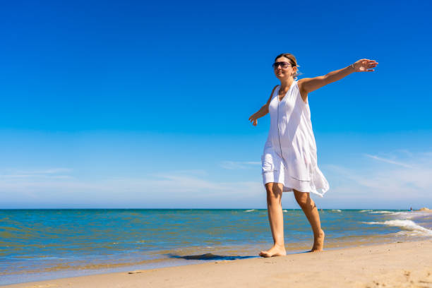 istock Beautiful woman walking on beach 1411862996