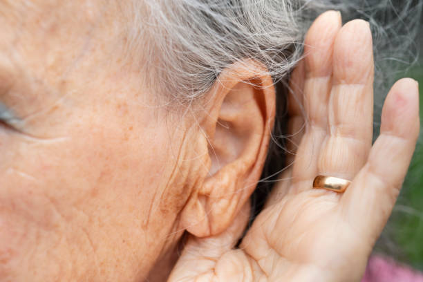 istock Hearing problems. Hand behind the ear to hear better. Hearing problems in older people, Close up of ear, ear and hand of deaf woman. Gesture to hear better in people with deafness 1411868618