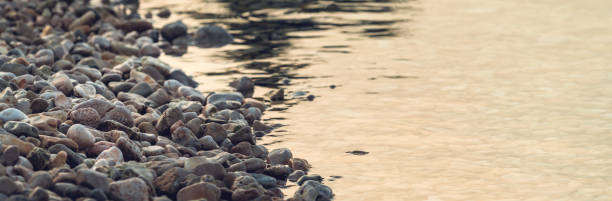 Beach pebbles and sea water in sunrise, summer vacation at seaside