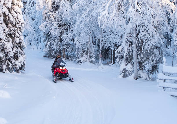 istock A man on a winter snowmobile rides through a snow-covered forest. 1411869819