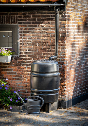 Rainwater tank and watering can in front of the house