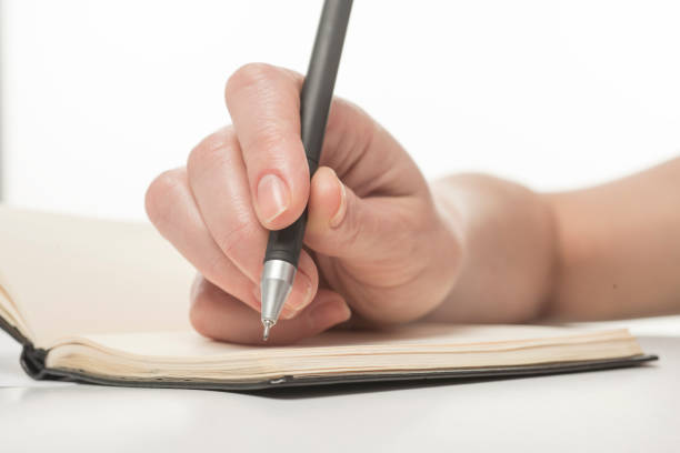 istock hand with a pen writes close-up isolated on a white background 1411877733