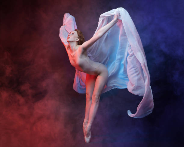 istock charming ballerina posing with chiffon fabric in a studio in colored smoke 1411878063