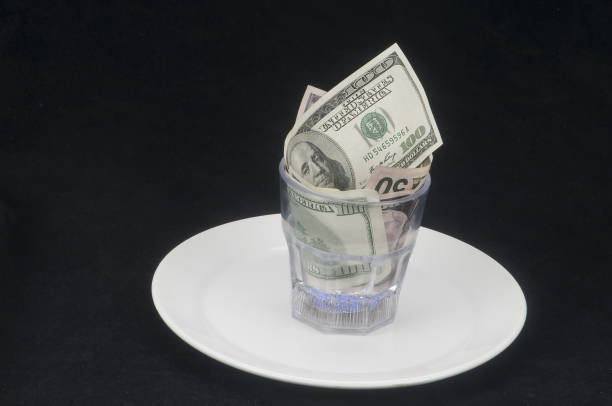 istock 100, 50 and 5 dollar bills on a plate inside a glass beaker. 1411879963