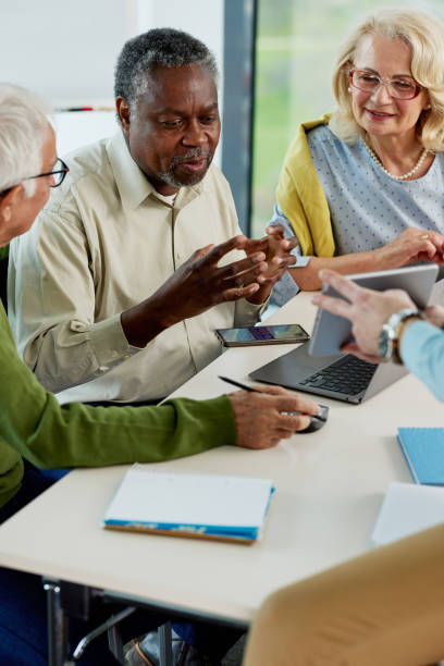 istock Young hipster educator teaching group of senior multiracial people using technology and the internet in the classroom. 1411881174
