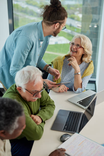 istock Young hipster educator teaching group of senior multiracial people using technology and the internet in the classroom. 1411881182