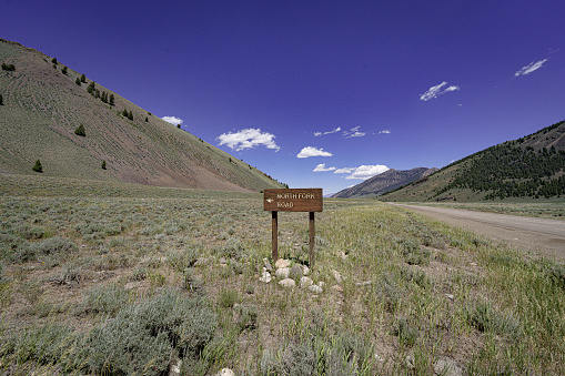 This photo shows a well-maintained US Forestry Road sign and road heading into the Challis National Forest in Idaho.  The Salmon-Challis National Forest covers over 4.3 million acres in east-central Idaho. Included within the boundaries of the Forest is 2.3 million acres of the Frank Church- River of No Return Wilderness Area, the largest contiguous wilderness area in the Continental United States.