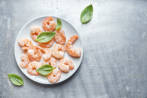 Shrimps on plate with basil on bright background. Top View