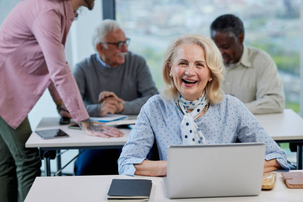 istock A happy female senior student sits in a classroom and does an assignment on the laptop while smiling at the camera. 1411881952