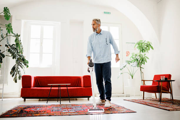 istock Man cleaning house with wireless vacuum cleaner 1411886327