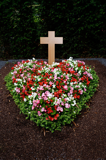 colorful heart shaped flower arrangement on a grave with wooden cross