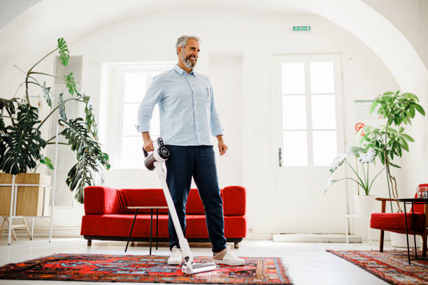 istock Man cleaning house with wireless vacuum cleaner 1411888270